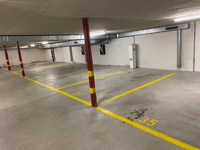A clean and empty parking lot with numbered parking spots and an access gate.