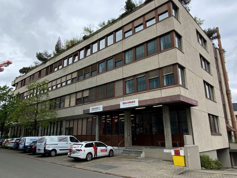 office building, grey facade, brown windows, several floors, parking lot, entrance