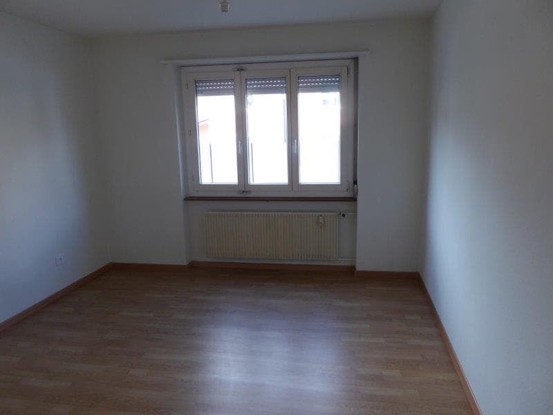 Spacious bedroom with large windows, hardwood flooring, and a radiator.
