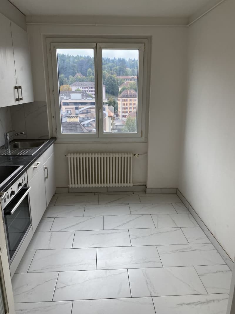 white tiles, white cabinets, kitchen sink, oven, white window with a city view
