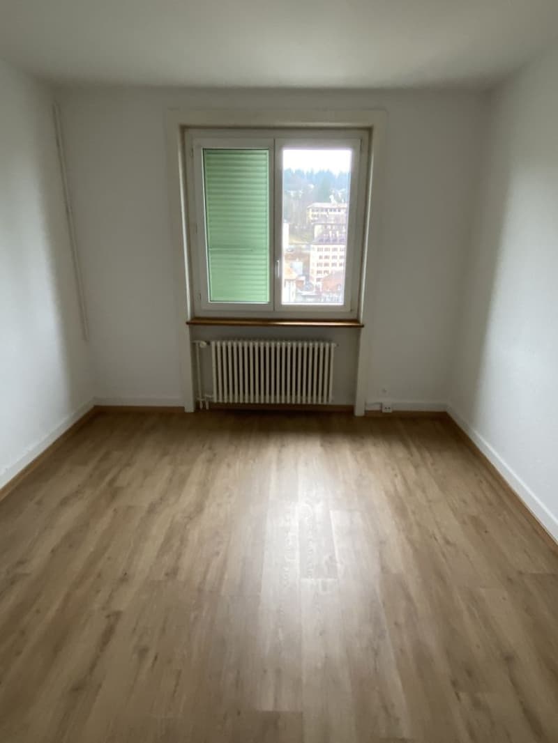 empty room, wooden floor, white walls, window with green shutters, radiator