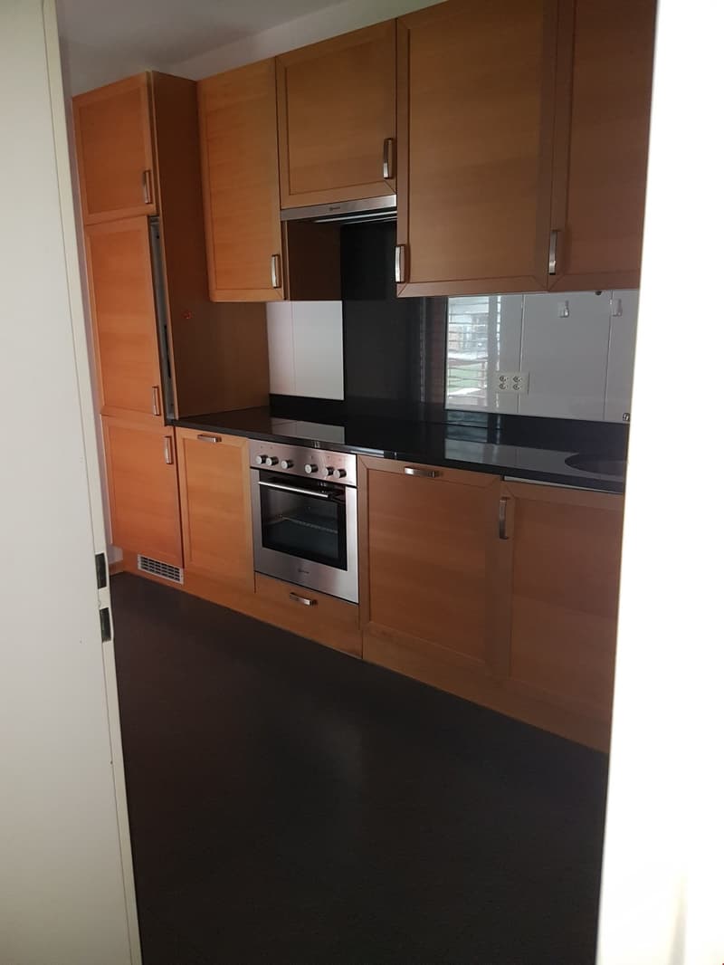 modern kitchen with stainless steel appliances, wooden cabinets, black countertops