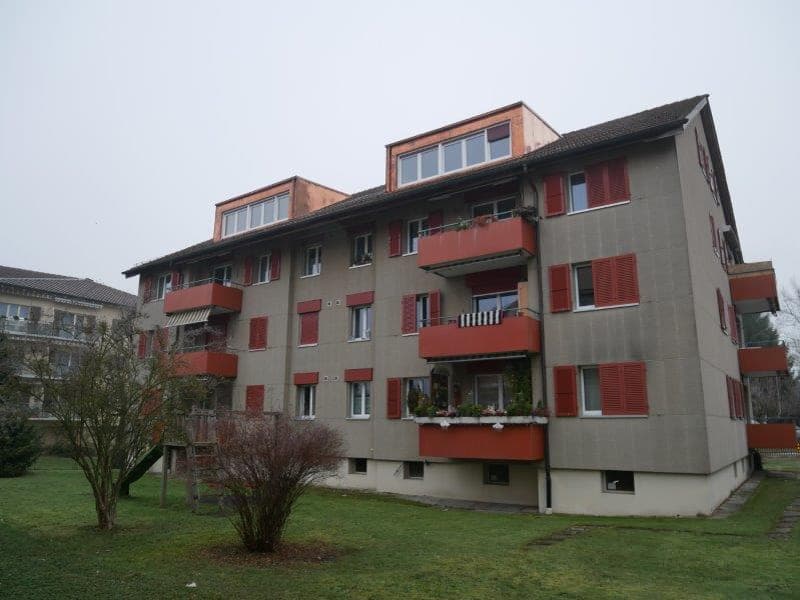 An apartment building with multiple balconies and red shutters
