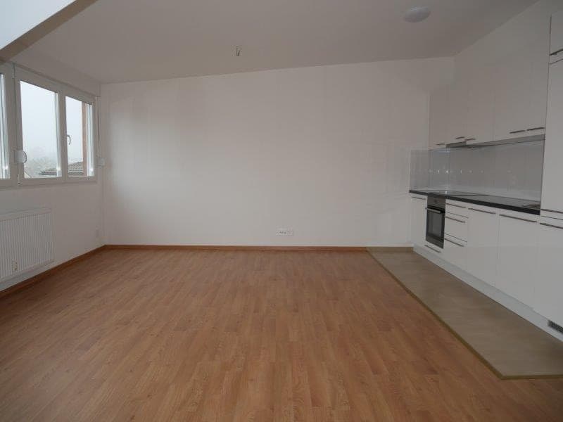 An empty kitchen with wooden floor, white walls, windows, and white cabinets.