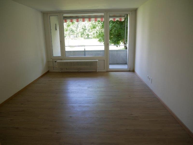 empty room, wooden floor, sliding doors to balcony, radiator, white walls
