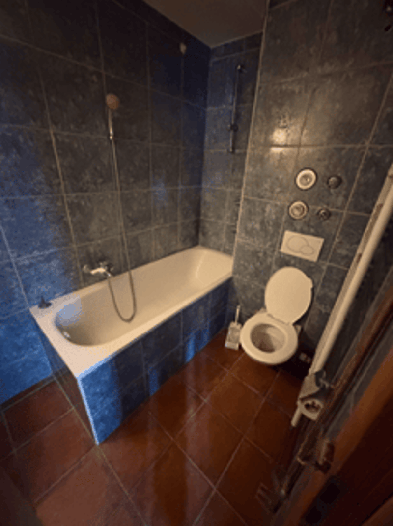Bathroom with bathtub, toilet, tiled walls and floor, overhead shower, wall mounted soap dish, wall mounted toilet paper holder