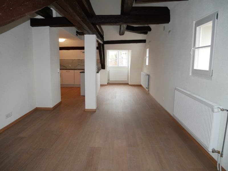hardwood floors, exposed wooden beams, white walls, windows, radiators, an open kitchen area with cabinets and countertop