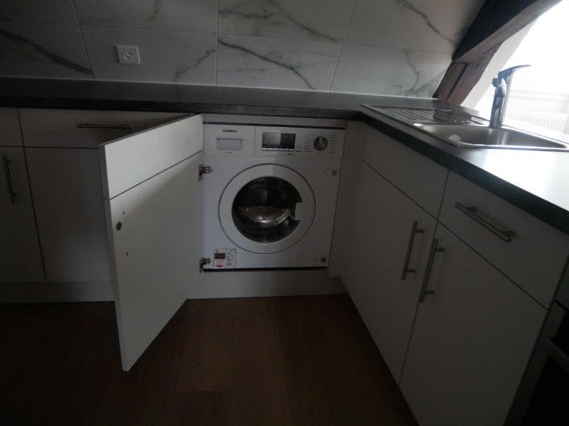 modern kitchen with marble tiles, white cabinets, dishwasher, washing machine, sink