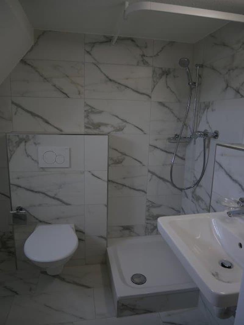 white marble tiles, shower, white sink, white toilet