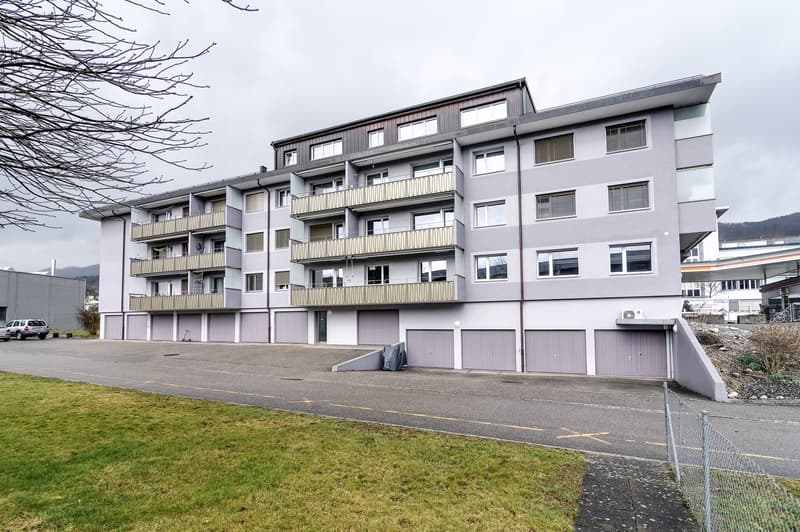 5 story apartment building, white walls, balconies, garage