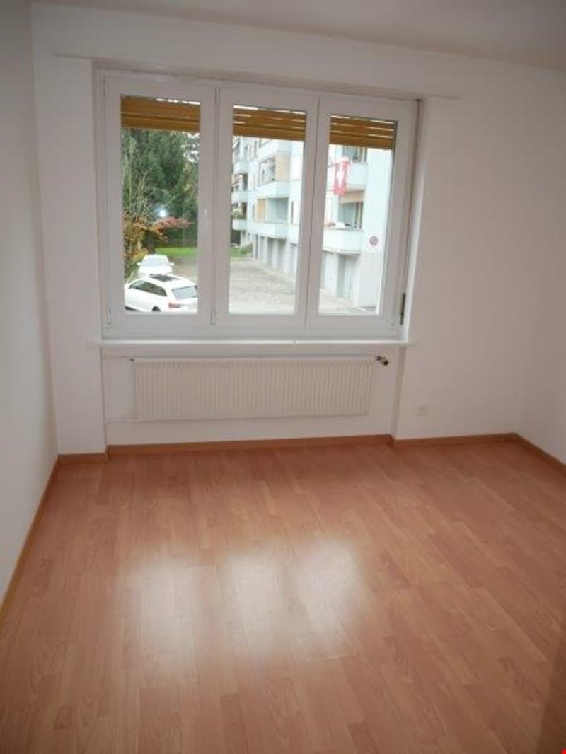 empty room, wooden floor, white walls, large window, radiator