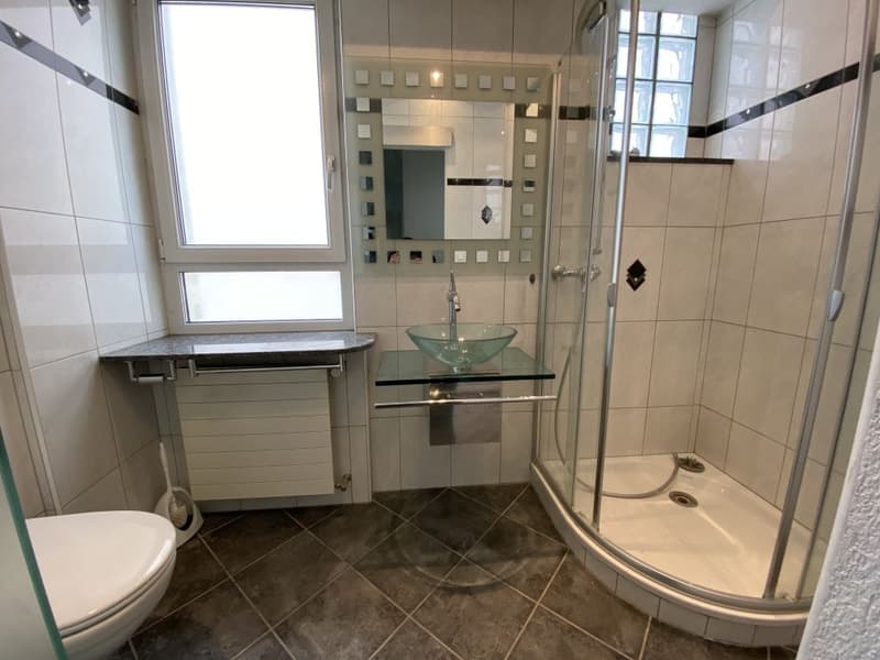 modern bathroom with white tiles, glass shower enclosure, glass sink, white toilet, mirror