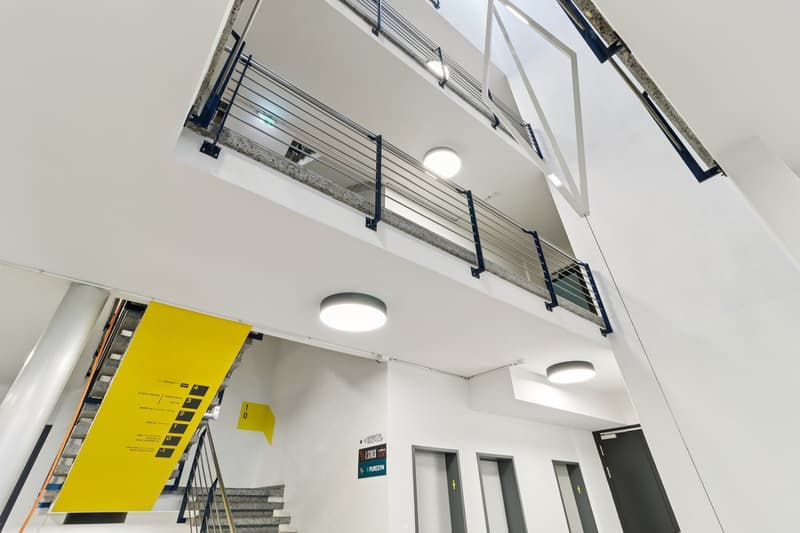 Atrium with open balconies, central staircase, two levels with doors