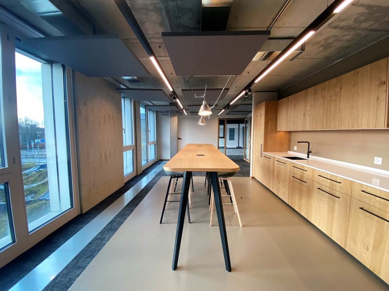 large windows, a wooden table, modern kitchen cabinets, pendant lamps