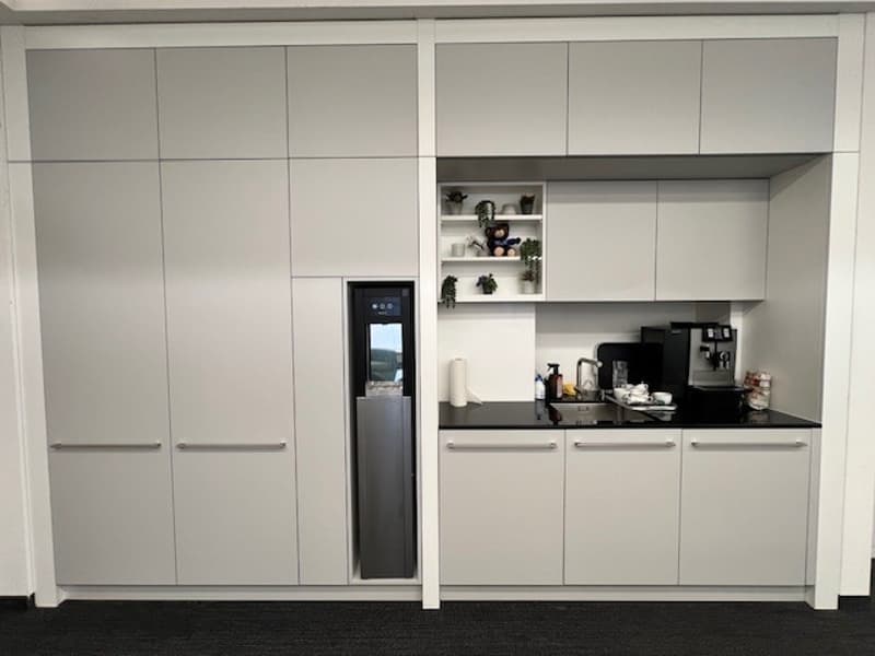 modern kitchen with white cabinets, black countertops, stainless steel appliances, and a refrigerator