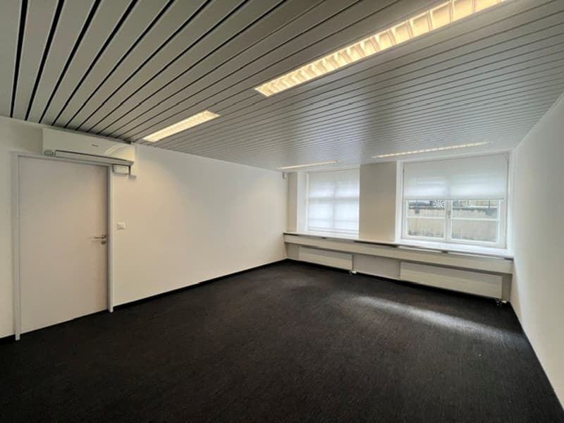 empty room, white walls, black floor, two windows, white door, air conditioning