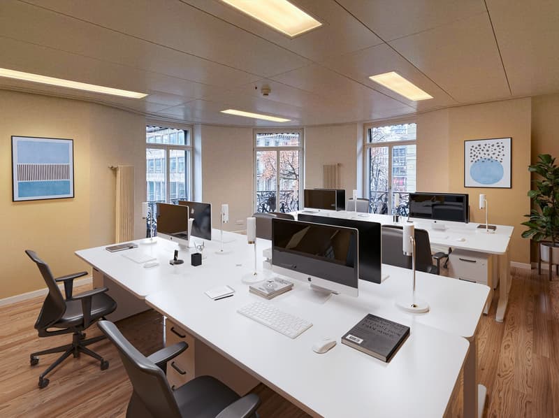 modern office with white desks, black chairs, monitors, keyboards, and books