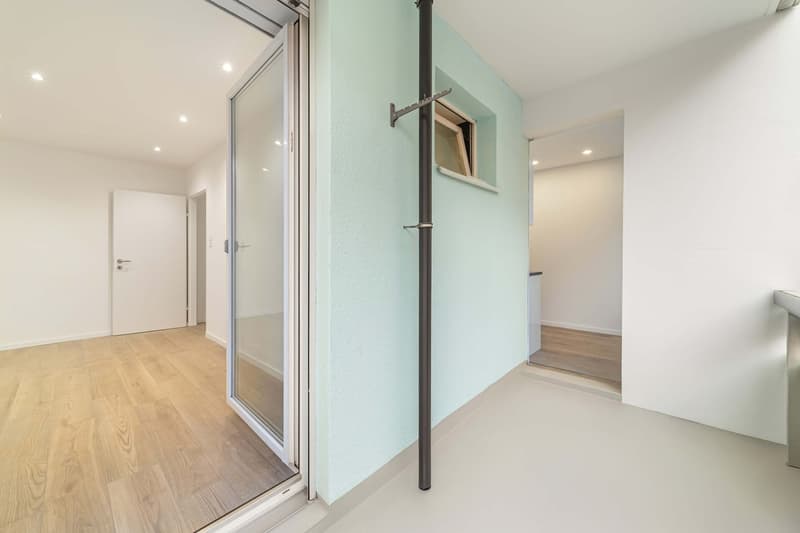 room has glass door, wooden floor, two entry ways, white walls, small window
