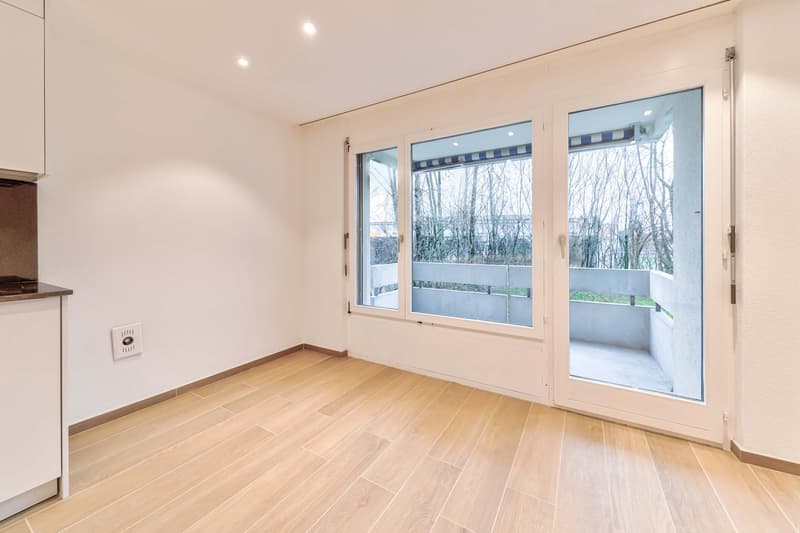 wooden floor, white walls, sliding glass doors leading to balcony, modern design