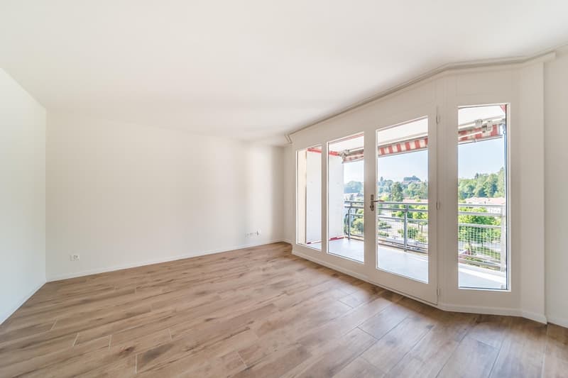 empty room with wooden floor, sliding doors leading to a balcony with metal railing