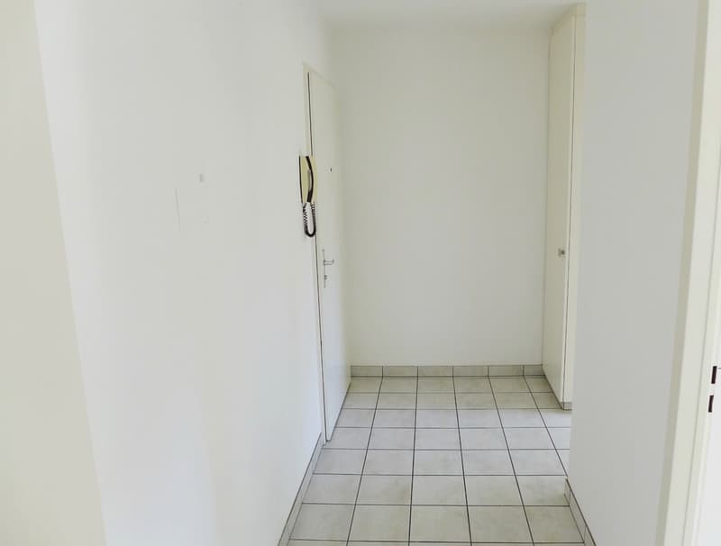 Empty hallway with white walls and tiled floor, two doors on either side