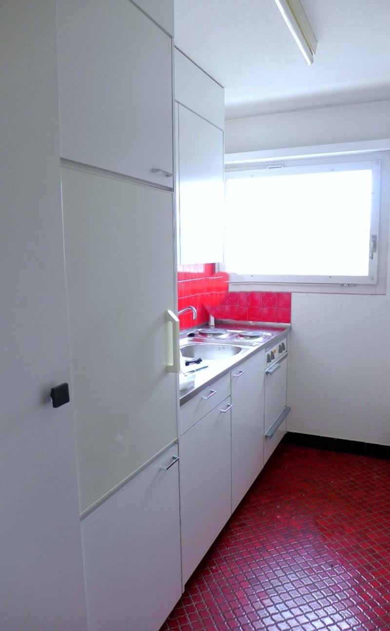 modern kitchen with white cabinets, red tiled floor, sink, stove, dishwasher, refrigerator