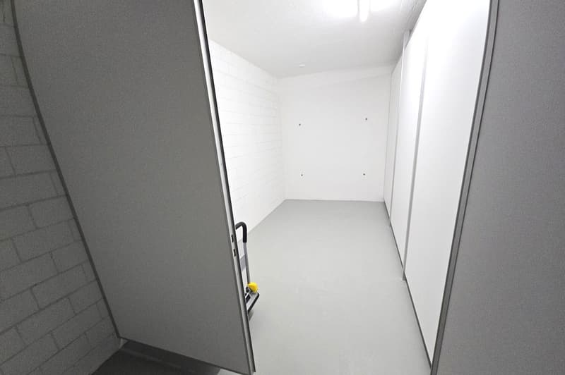 empty room with open door, floor on raised level, tile floor, white walls