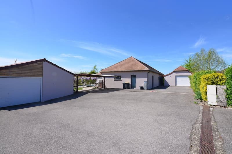 House with 2 garages, driveway, trash bins, and a covered area with a pergola