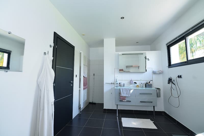 modern bathroom, white walls, black tiles, vanity with drawers, mirror, towel rack, window, towel hanging on the wall