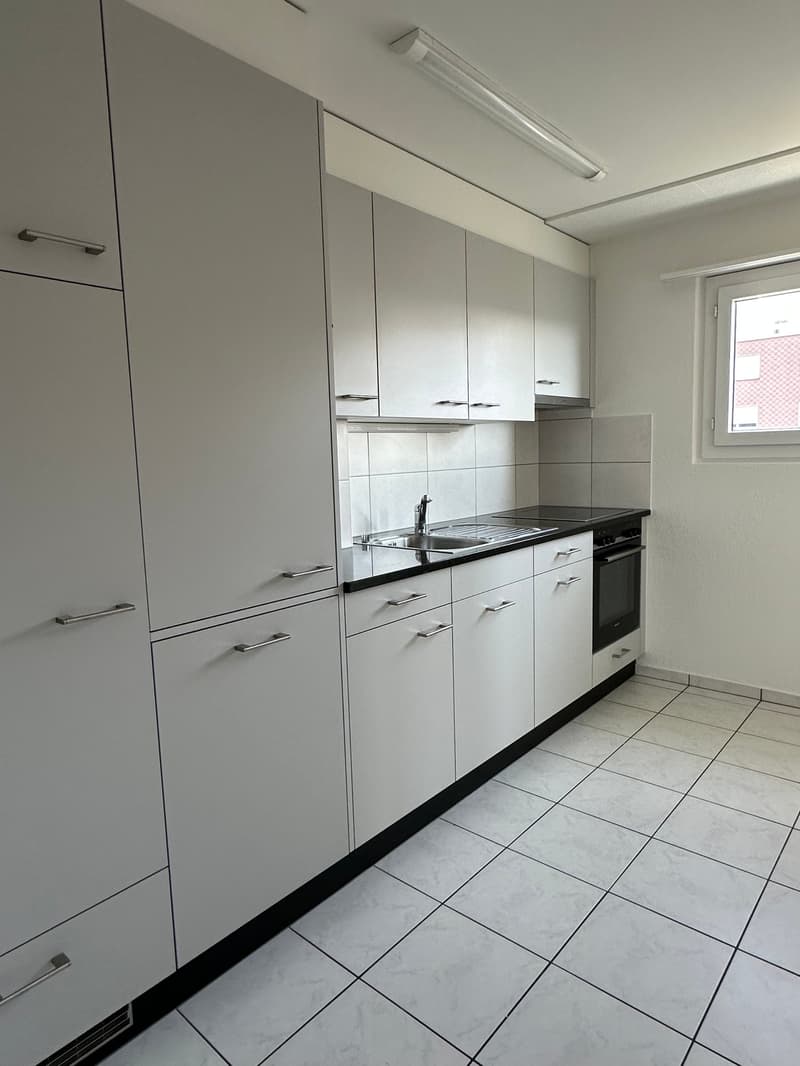 Modern minimalist kitchen with gray cabinets, white countertops, black trim, integrated appliances, tiled floor
