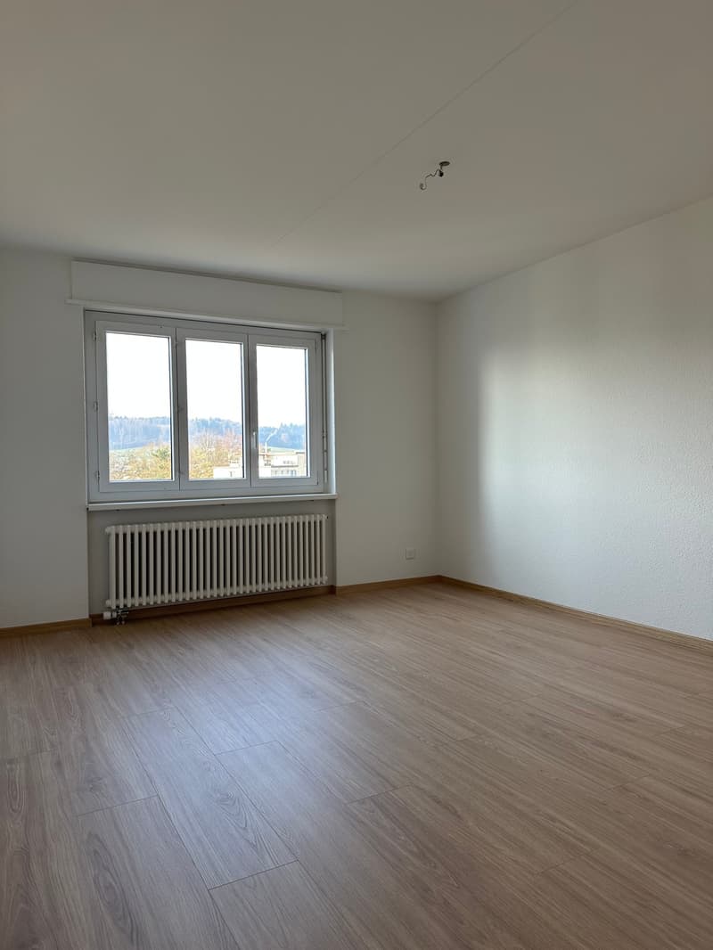 room with hardwood floors, large window, and white walls
