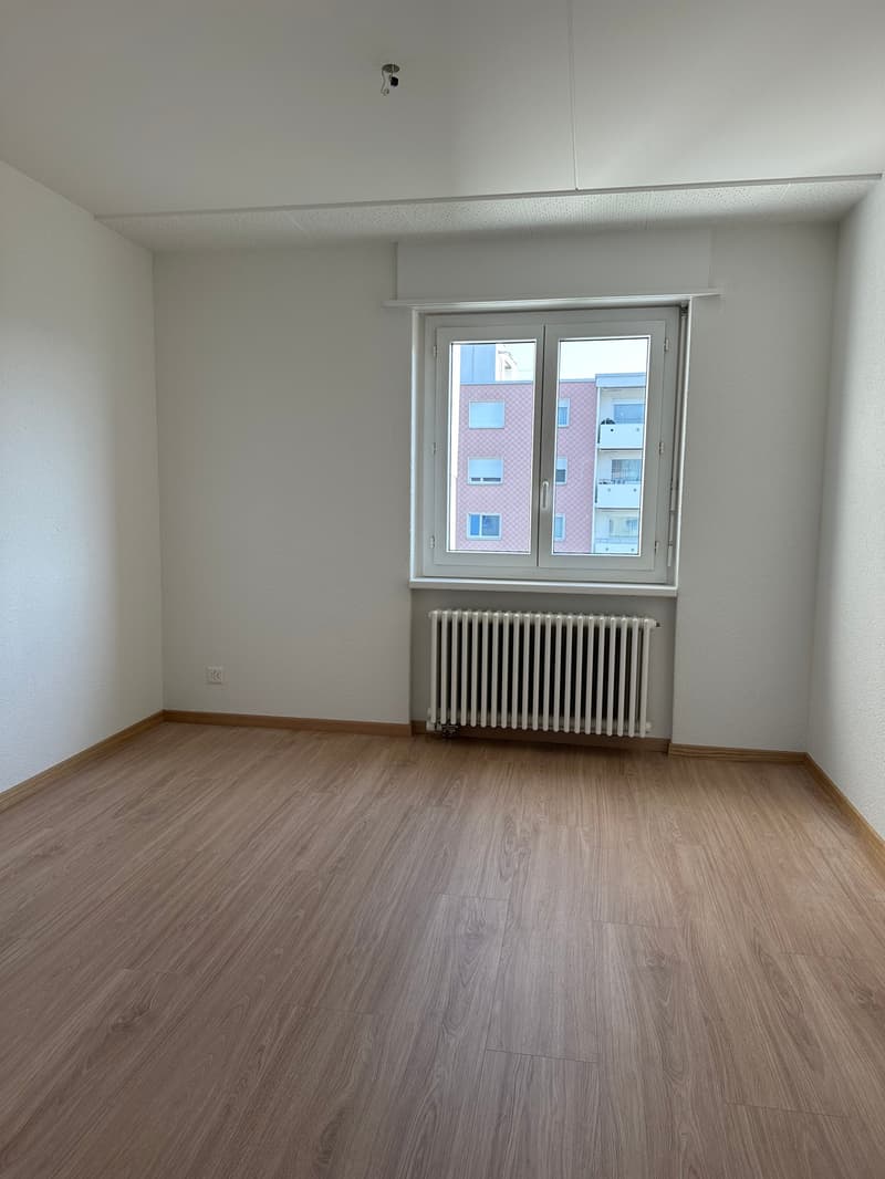 empty room with wooden floor, large window, and white walls