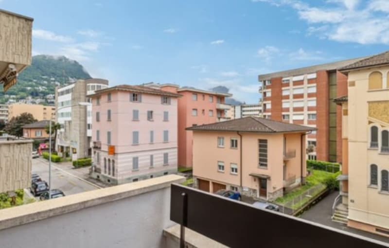 Several apartment buildings, balcony, street view, parked cars, mountain in the background