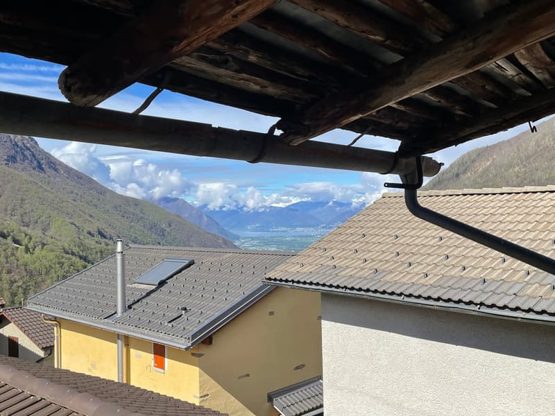 exterior of a yellow house with gray roof, solar panels, a neighboring house with a white wall, view of mountains