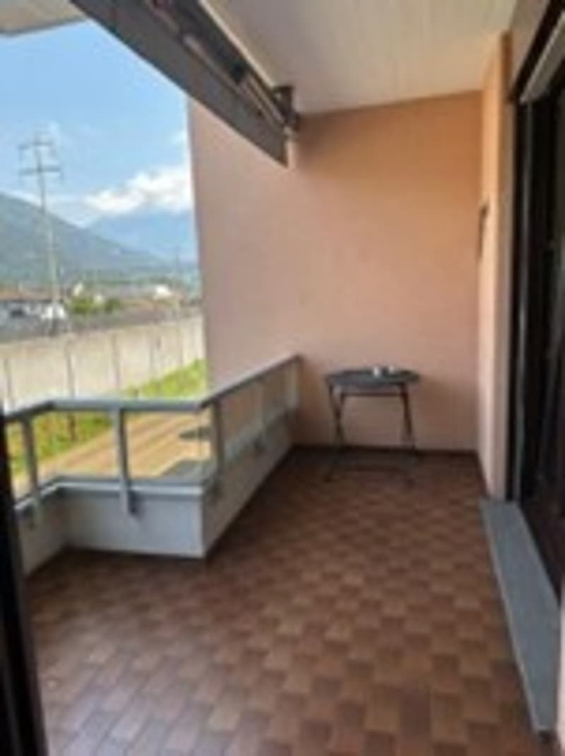 A balcony with tile flooring, metal railing, a small table, and an expansive mountain view.