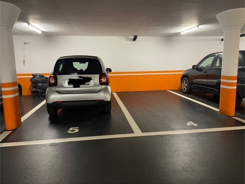 Underground parking lot with two parked cars, parking spots numbered 4 and 5.