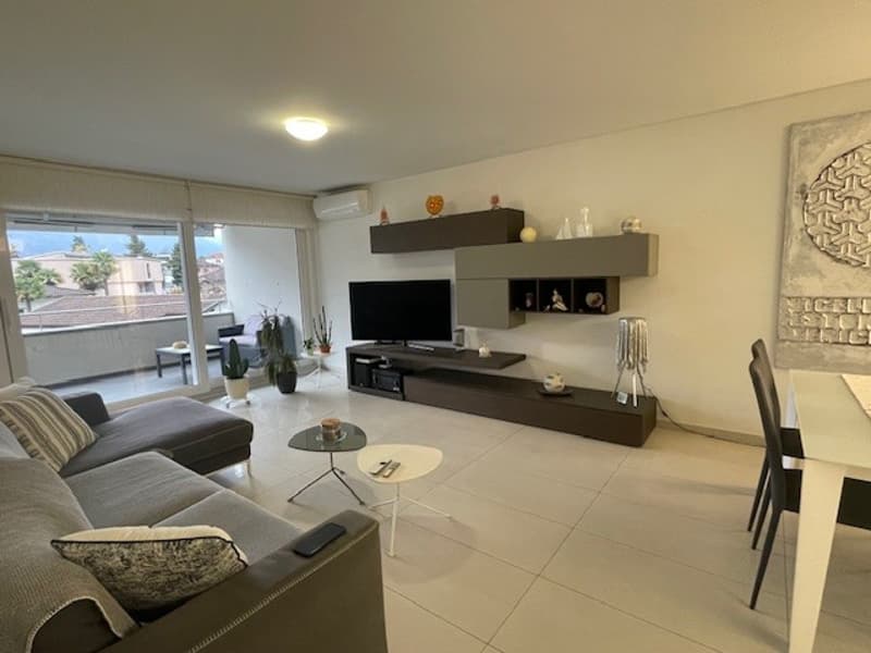 modern living room, white tiles, gray couch, TV, coffee table, side table, dining table with chairs, sliding doors leading to balcony