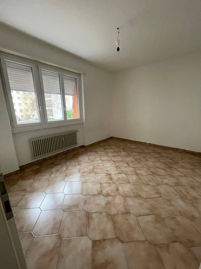empty room, brown tiles, white walls, window with blinds, radiator, ceiling lamp