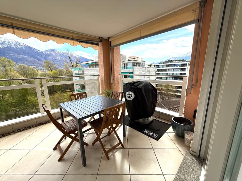 Balcony with table and chairs, covered by awning, covered floor, view of mountains