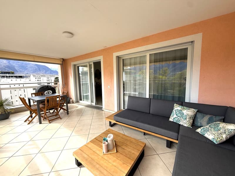 Balcony with table and chairs, couch, coffee table, tiled floor, sliding glass doors, mountain view