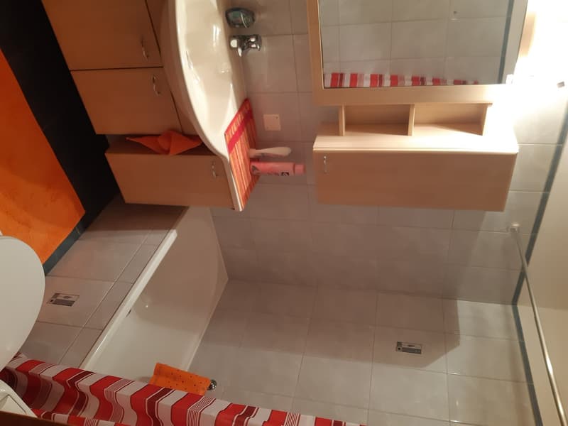 Bathroom with white tiles, vanity unit with drawers, and a washing machine visible.