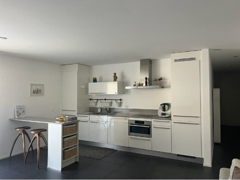 modern kitchen, white cabinets, stainless steel appliances, black tiled floor, island with stools, picture frame, rug