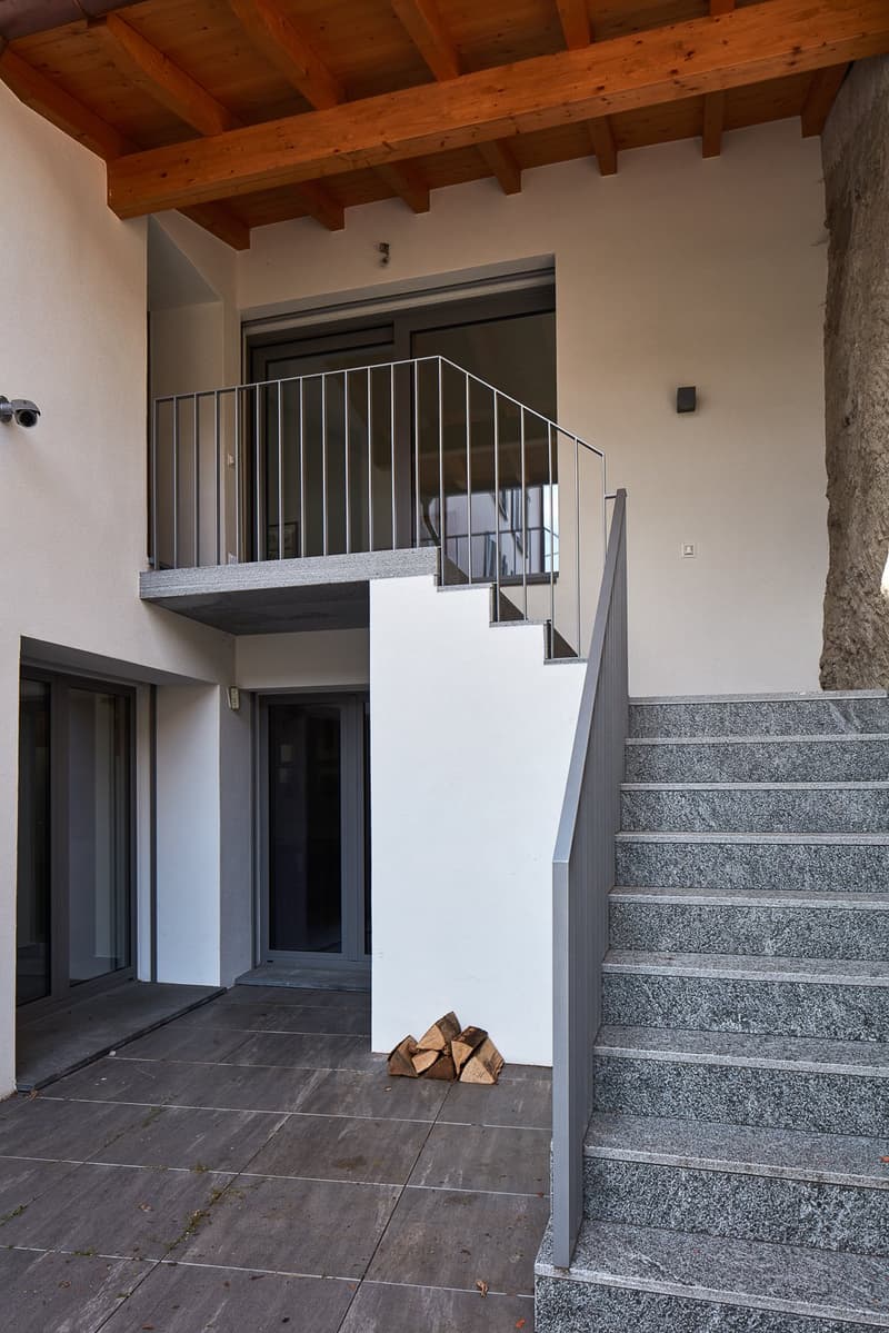 modern house, white walls, gray granite steps, wooden ceiling, balcony, paved entrance