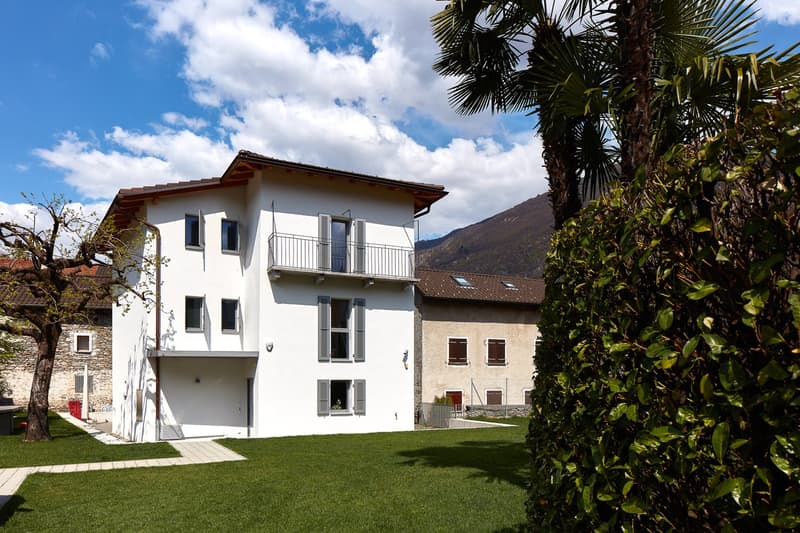 2 story white house, brown roof, balcony, windows, garden, mountain view