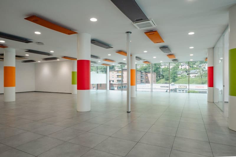 empty room, gray tiled floor, large windows, glass doors, columns, large air vent ducts