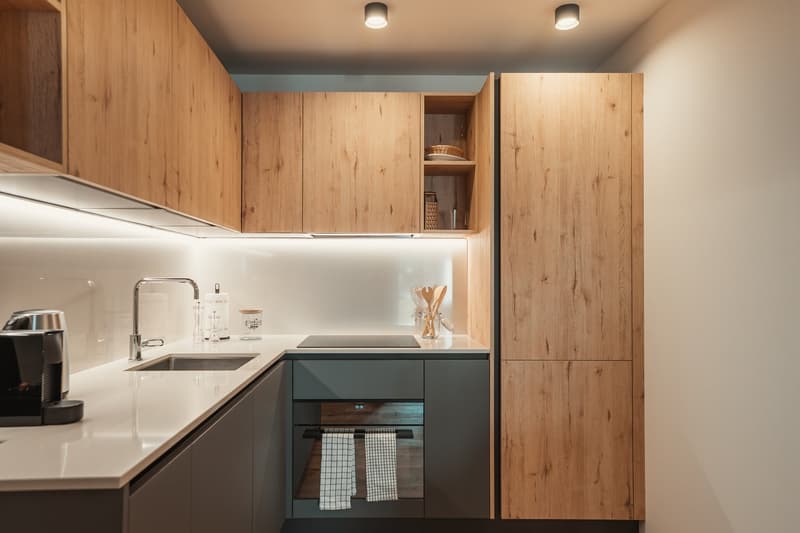Modern kitchen with wooden cabinets, white countertops, and a sleek black stove.
