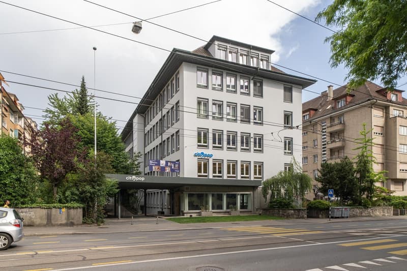 5-story office building with a modern facade, located on a street with trees and other residential buildings. The building has the CityCoop logo displayed on the ground floor.