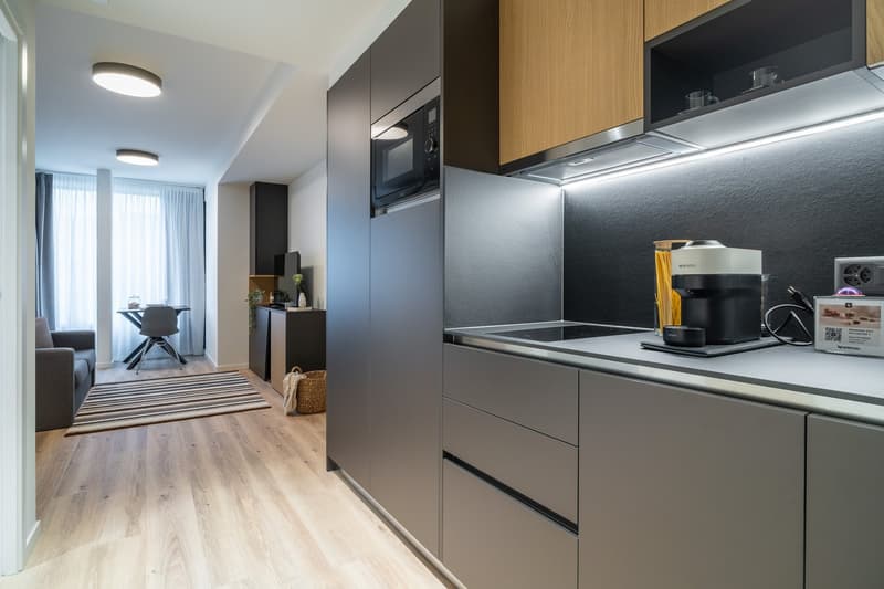 modern kitchen with wooden floor, granite countertops, built-in appliances, microwave, stove, and refrigerator, wooden cabinets
