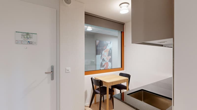 Small kitchen with wooden table and chairs, dishwasher, and a map on the wall