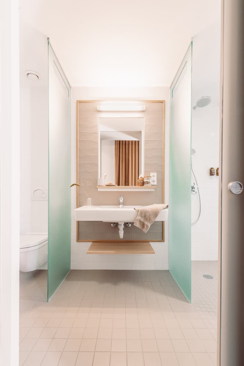 Modern bathroom with white walls, glass shower enclosure, vanity with sink, and wooden accents.
